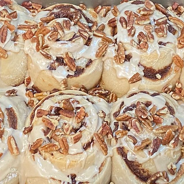 Sourdough cinnamon bun topped with toasted pecans and maple glaze