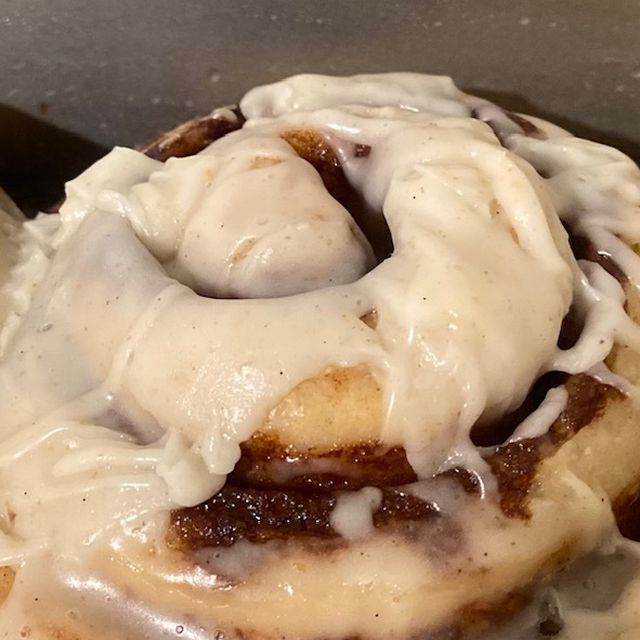 Sourdough cinnamon bun under a thick white vanilla glaze