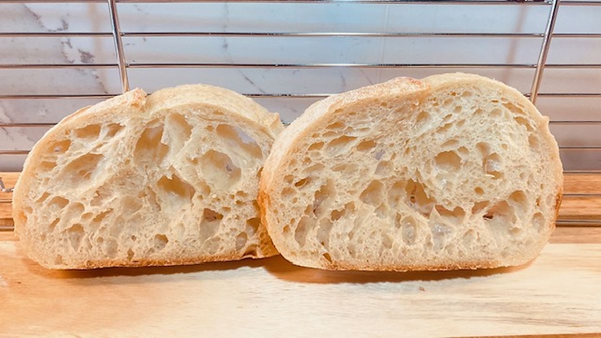 A sourdough loaf cut open showing an open irregular crumb with glossy translucent walls